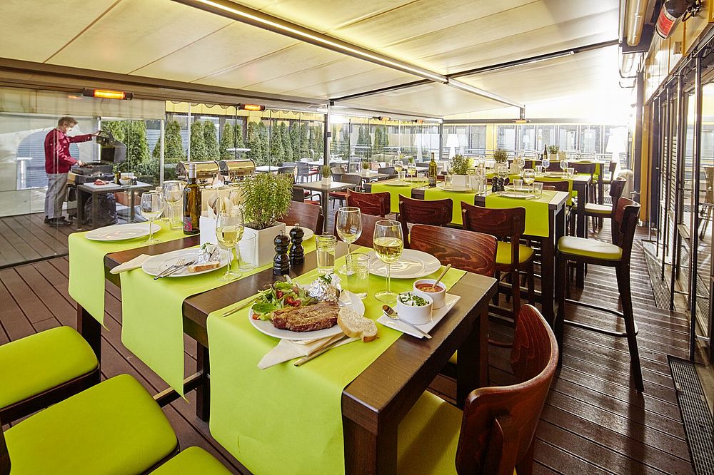 Wintergarten mit Grill und gedeckten Tischen